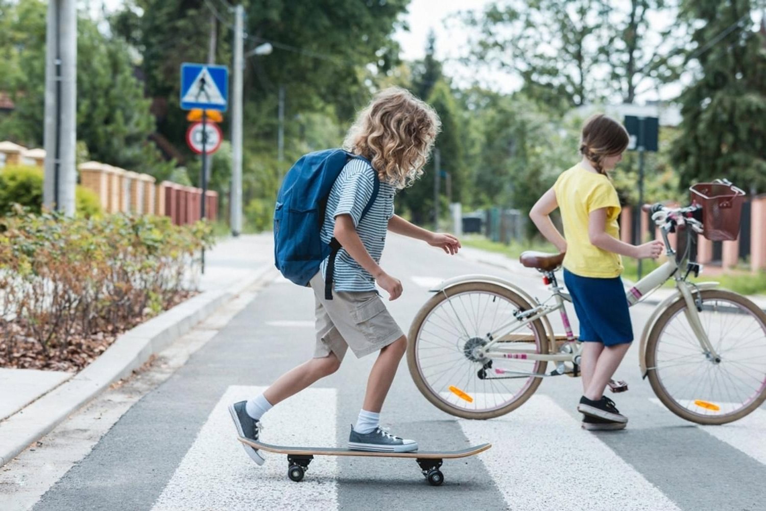 Two children crossing a pedestrian crossing on a skateboard and bicycle, illustrating everyday risks family health insurance covers in the UAE